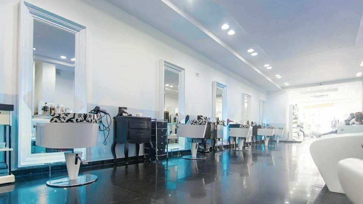 Salón blanco con espejos de marco blanco y sillas con estampado barroco