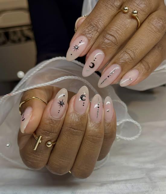 Uñas acrílicas nude con nail art de lunas y estrellas